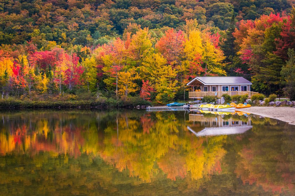 Boathouse and fall colors reflecting in Echo Lake, in Franconia